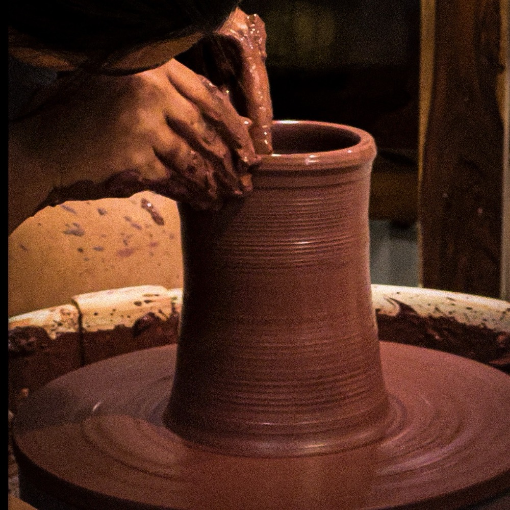 Hands shaping pottery on a wheel